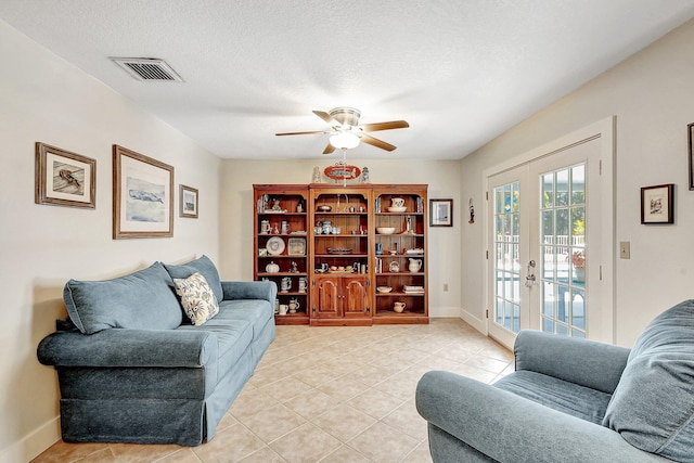 living room featuring ceiling fan, light tile patterned flooring, a textured ceiling, and french doors