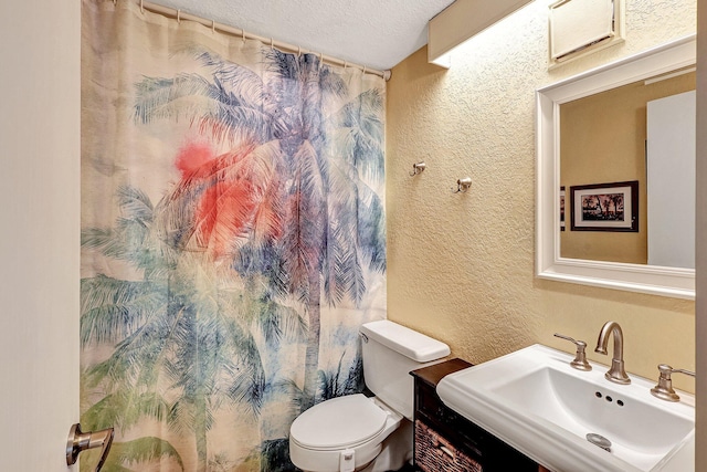 bathroom with sink, a textured ceiling, and toilet