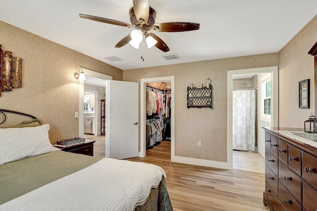 bedroom with ceiling fan, light wood-type flooring, a spacious closet, and a closet