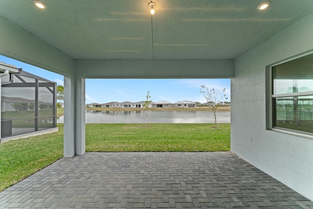 view of patio with a water view and glass enclosure