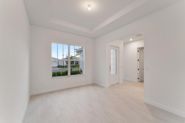 unfurnished room with light hardwood / wood-style floors and a raised ceiling