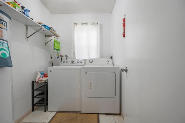 laundry area with light tile patterned floors, a textured ceiling, and independent washer and dryer