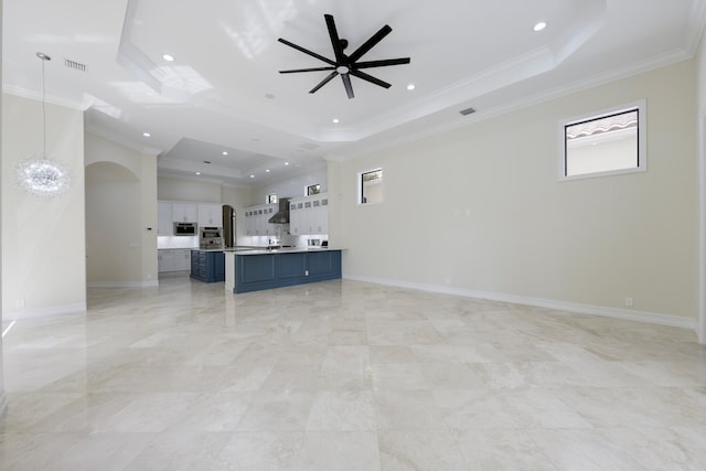 unfurnished living room featuring a tray ceiling, crown molding, and ceiling fan