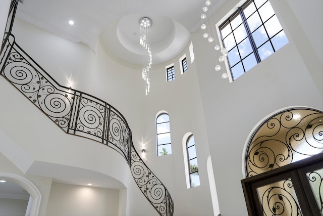 stairway featuring a towering ceiling and crown molding