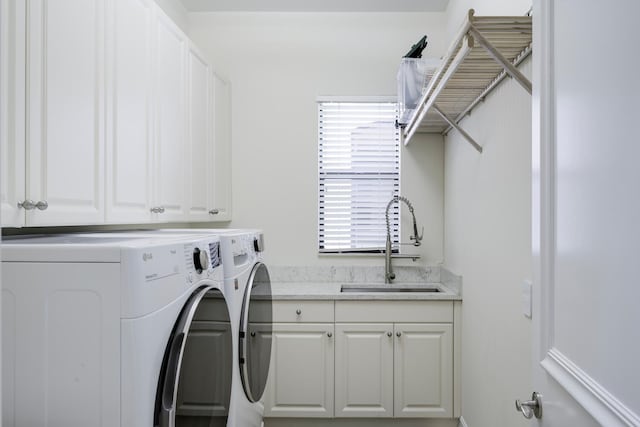 clothes washing area featuring washing machine and dryer, sink, and cabinets