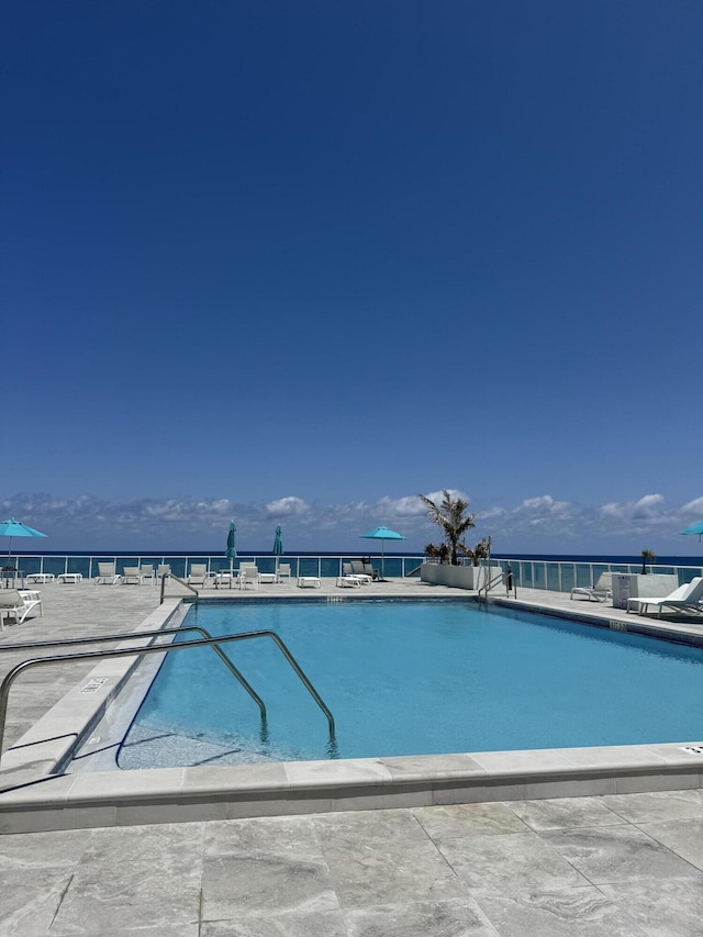 pool featuring a water view and a patio