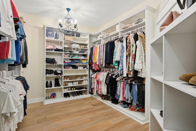 walk in closet with a notable chandelier and light wood-type flooring