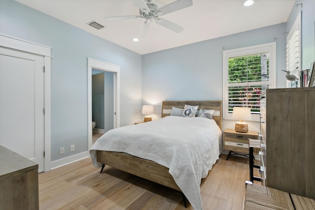 bedroom featuring ceiling fan, ensuite bathroom, and light hardwood / wood-style flooring