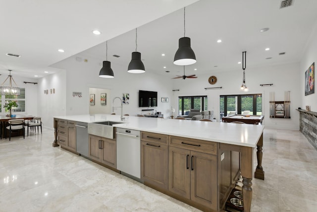 kitchen featuring white dishwasher, sink, hanging light fixtures, and a large island with sink