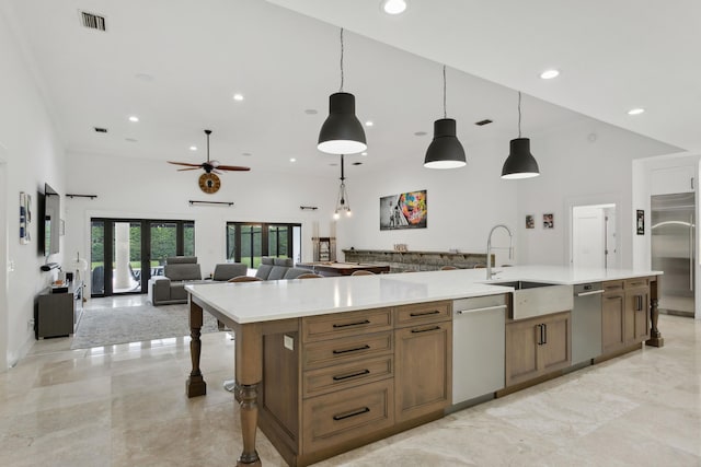 kitchen featuring stainless steel appliances, decorative light fixtures, sink, and a large island with sink