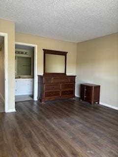 unfurnished bedroom with a textured ceiling and dark wood-type flooring