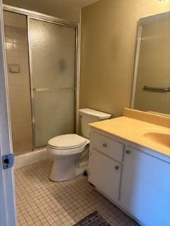 bathroom featuring tile patterned flooring, vanity, an enclosed shower, and toilet