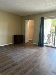 unfurnished bedroom featuring a textured ceiling, a walk in closet, dark hardwood / wood-style floors, and a closet