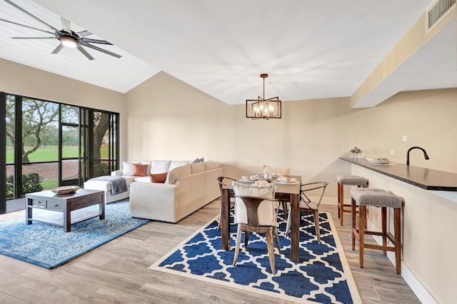 dining room with ceiling fan with notable chandelier, vaulted ceiling, and sink