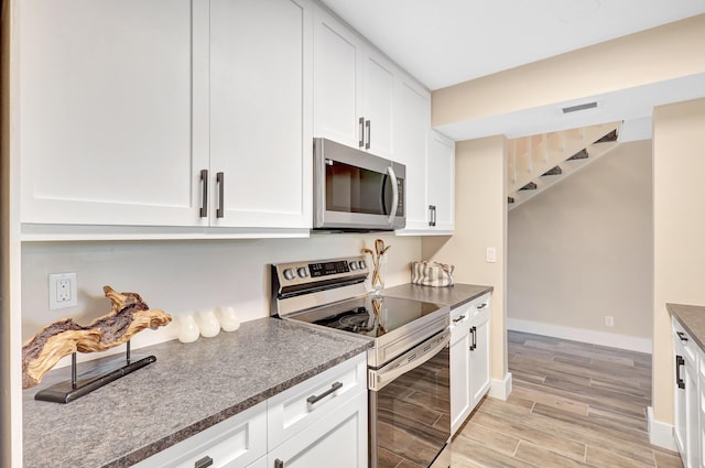 kitchen with white cabinets, light wood-type flooring, and stainless steel appliances