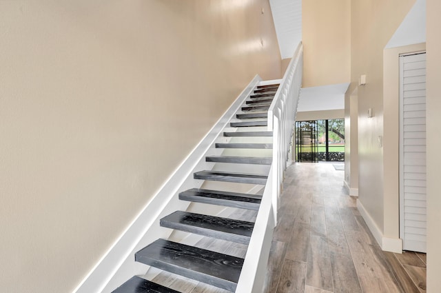 staircase featuring a high ceiling and hardwood / wood-style flooring