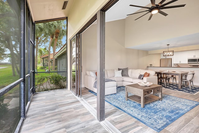 sunroom with ceiling fan with notable chandelier