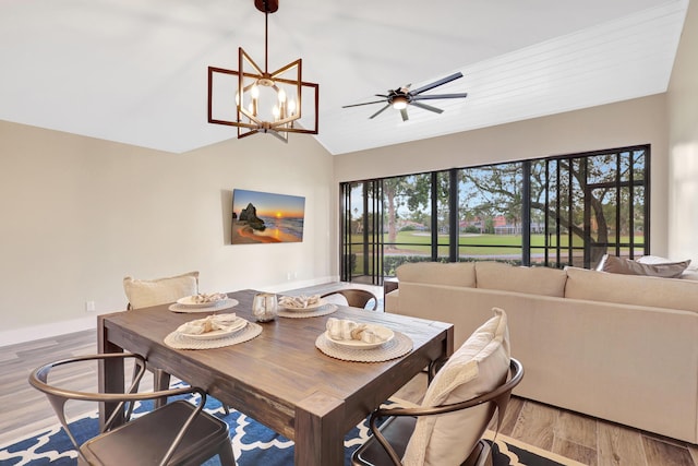 dining room featuring wood-type flooring, ceiling fan with notable chandelier, and vaulted ceiling