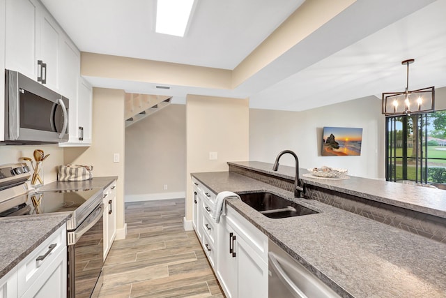 kitchen with an inviting chandelier, sink, decorative light fixtures, white cabinetry, and stainless steel appliances