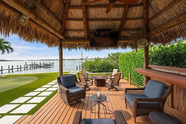 wooden deck with a fire pit, ceiling fan, a gazebo, and a water view