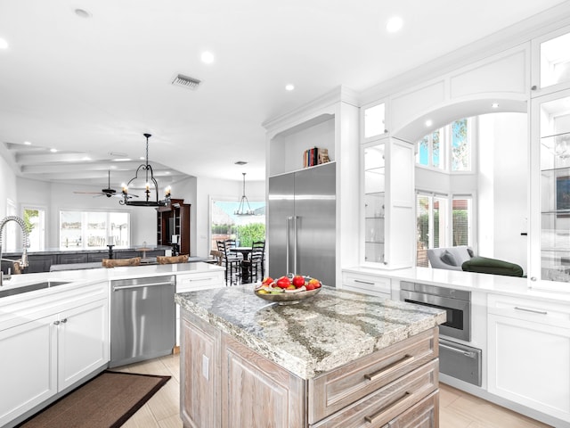 kitchen with a center island, white cabinets, stainless steel appliances, and sink