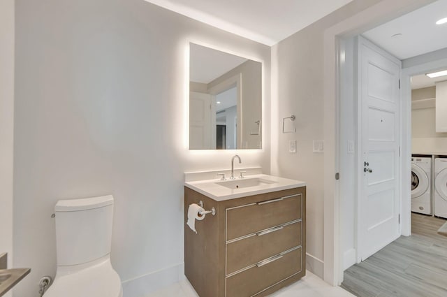 bathroom with separate washer and dryer, vanity, hardwood / wood-style floors, and toilet