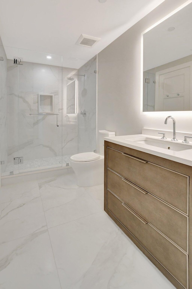 bathroom featuring vanity, a shower with shower door, and toilet