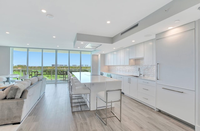 kitchen with a breakfast bar, white cabinetry, tasteful backsplash, a center island, and expansive windows