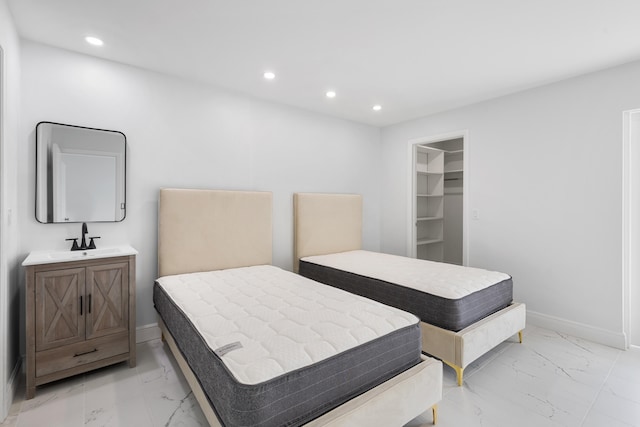 tiled bedroom with a spacious closet, sink, and a closet