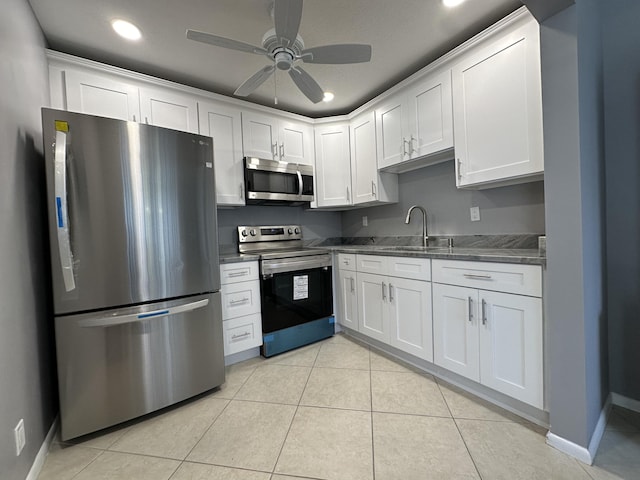 kitchen with ceiling fan, sink, light tile patterned floors, stainless steel appliances, and white cabinets