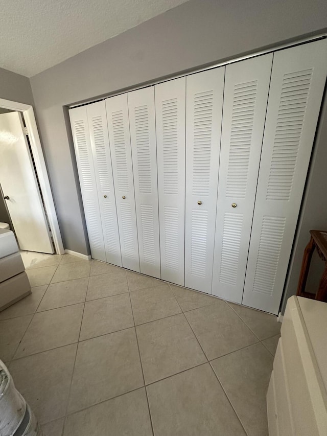 tiled bedroom featuring a textured ceiling and a closet