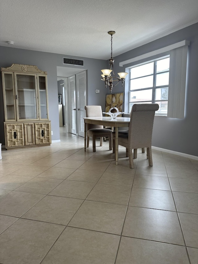 dining space featuring light tile patterned flooring, a textured ceiling, and an inviting chandelier