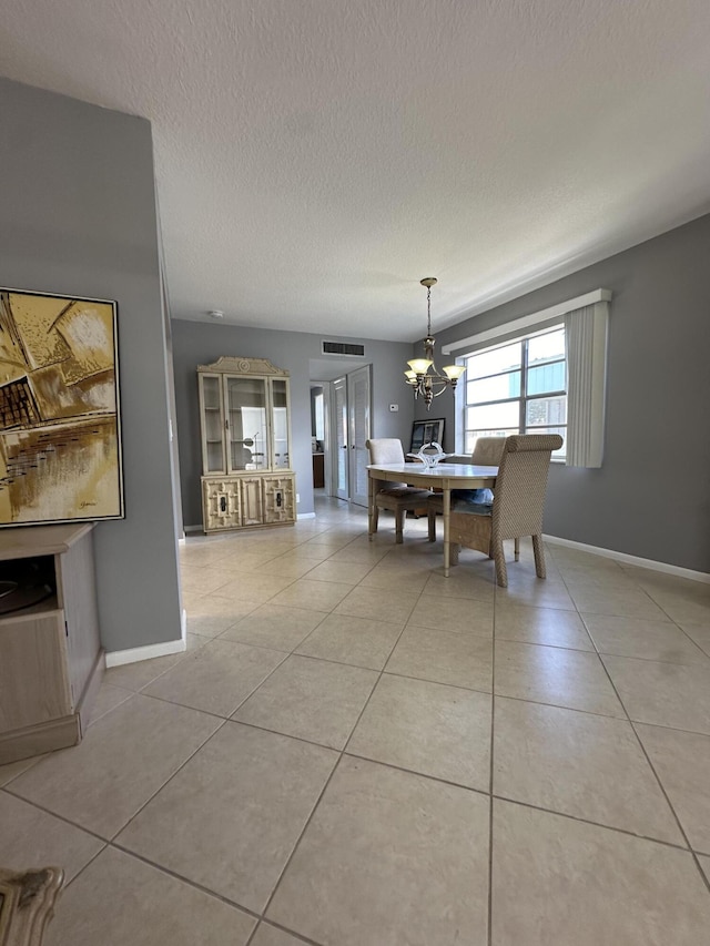 unfurnished dining area with a textured ceiling, a chandelier, and light tile patterned flooring