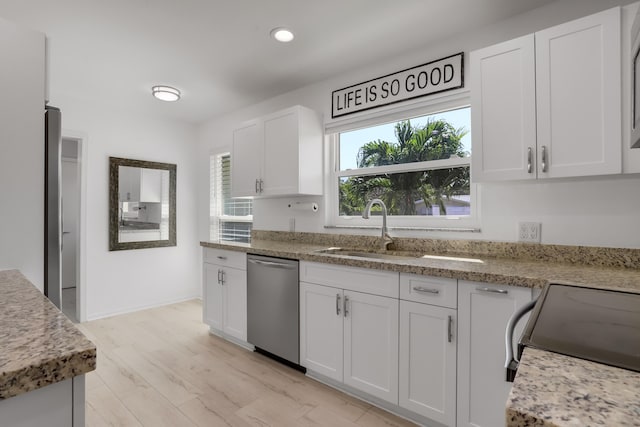 kitchen featuring light stone counters, light hardwood / wood-style floors, dishwasher, white cabinets, and sink