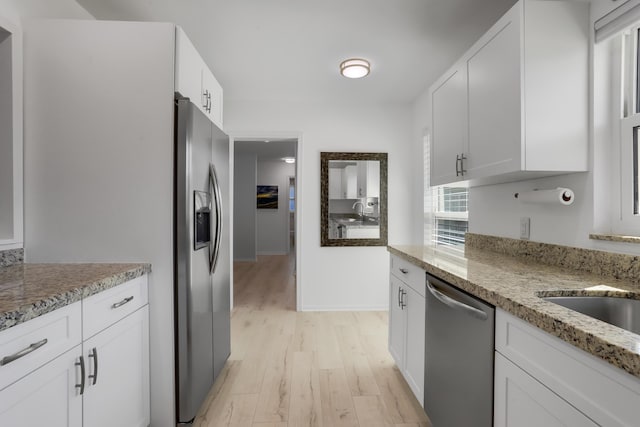 kitchen featuring appliances with stainless steel finishes, white cabinets, light stone countertops, and light hardwood / wood-style flooring