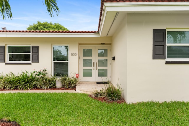 doorway to property featuring french doors and a lawn