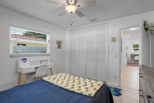 bedroom with ceiling fan, a closet, light hardwood / wood-style flooring, and multiple windows