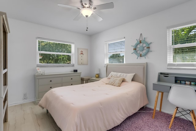 bedroom featuring ceiling fan, multiple windows, and light hardwood / wood-style flooring