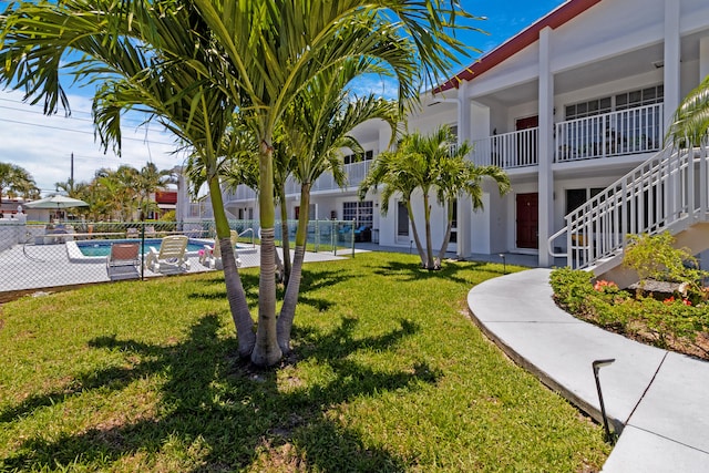 view of property's community featuring a yard, a swimming pool, and a patio area