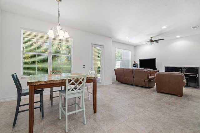 tiled dining space with ceiling fan with notable chandelier and a textured ceiling