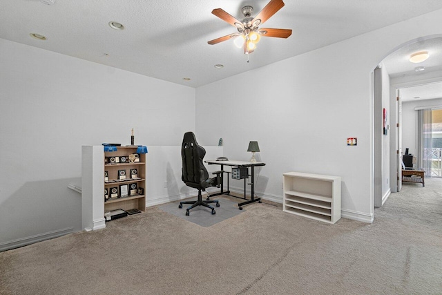 carpeted home office with ceiling fan and a textured ceiling