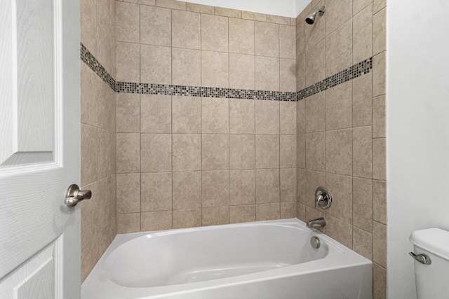 bathroom featuring tiled shower / bath combo and toilet