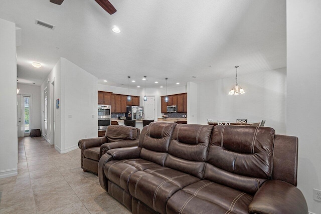 living room featuring ceiling fan with notable chandelier and light tile patterned flooring