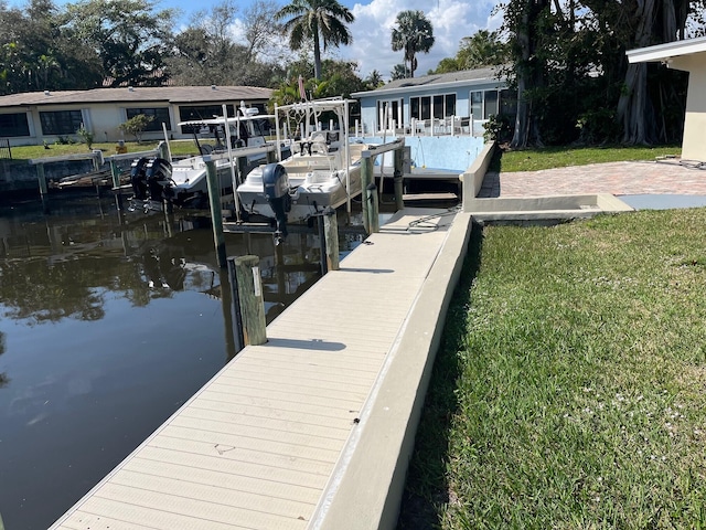 dock area with a water view, a yard, and boat lift