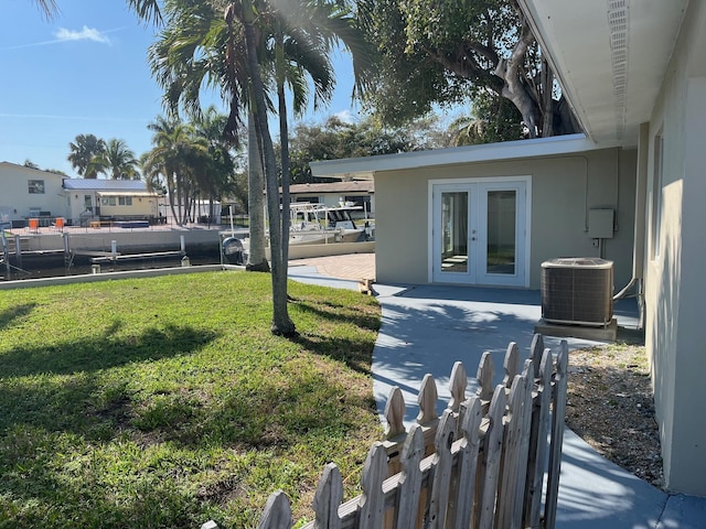 view of yard with french doors, fence, and central AC unit