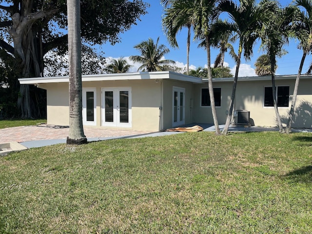 rear view of house with french doors, a yard, stucco siding, a patio area, and cooling unit