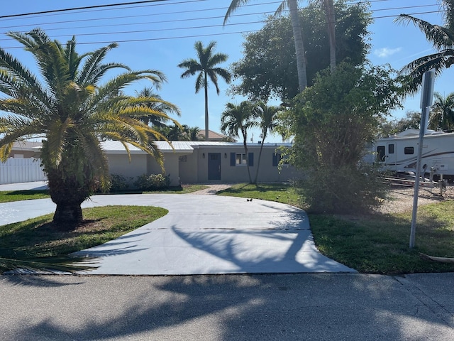 view of front of home featuring fence, curved driveway, and stucco siding