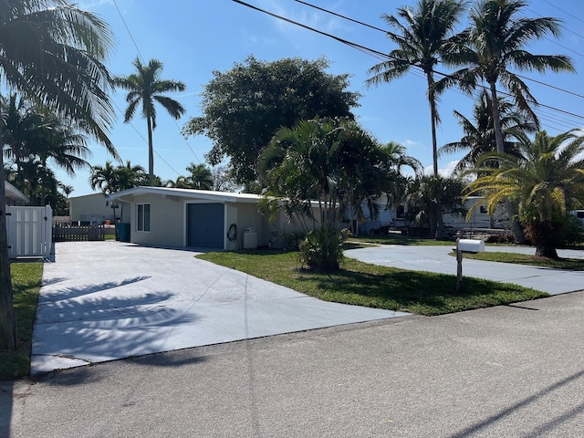 view of front facade with driveway, fence, a front lawn, and stucco siding