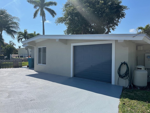 view of home's exterior with fence, concrete driveway, and stucco siding