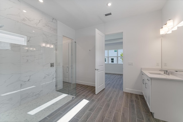 bathroom featuring a shower with door and vanity